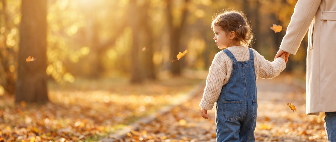 Meisje in denim tuinbroek loopt hand in hand door het herfstpark